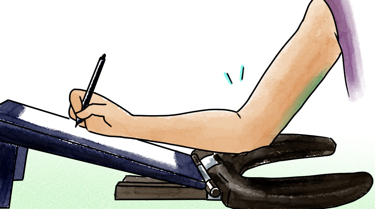 Hand drawing on a slanted monitor, with elbow resting on a soft arm support.